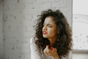 A brunette woman showing an expression of disgust against a brick wall.